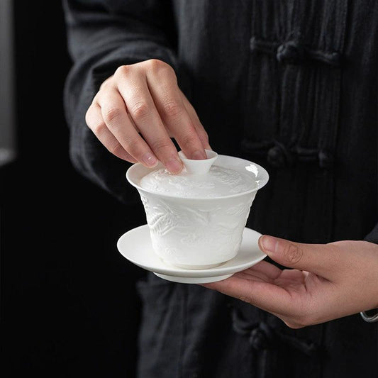 White porcelain gaiwan with embossed dragon design on saucer