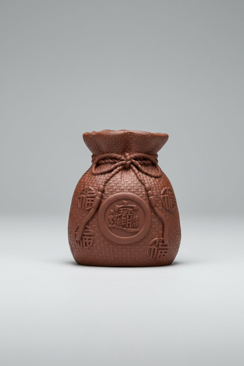 “Orange clay pouch tea figurine with coin motif”