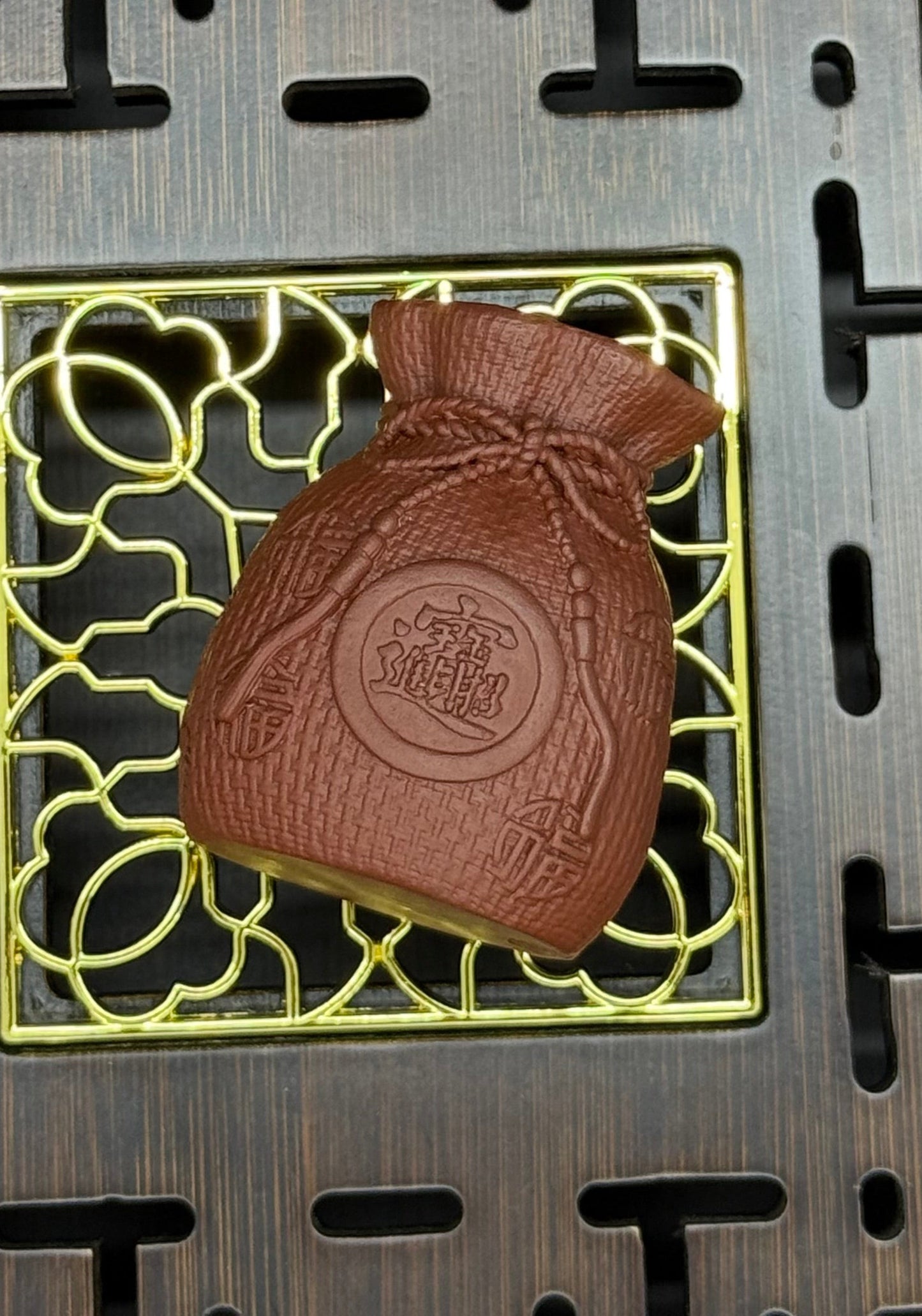 “Orange clay pouch tea figurine with coin motif”