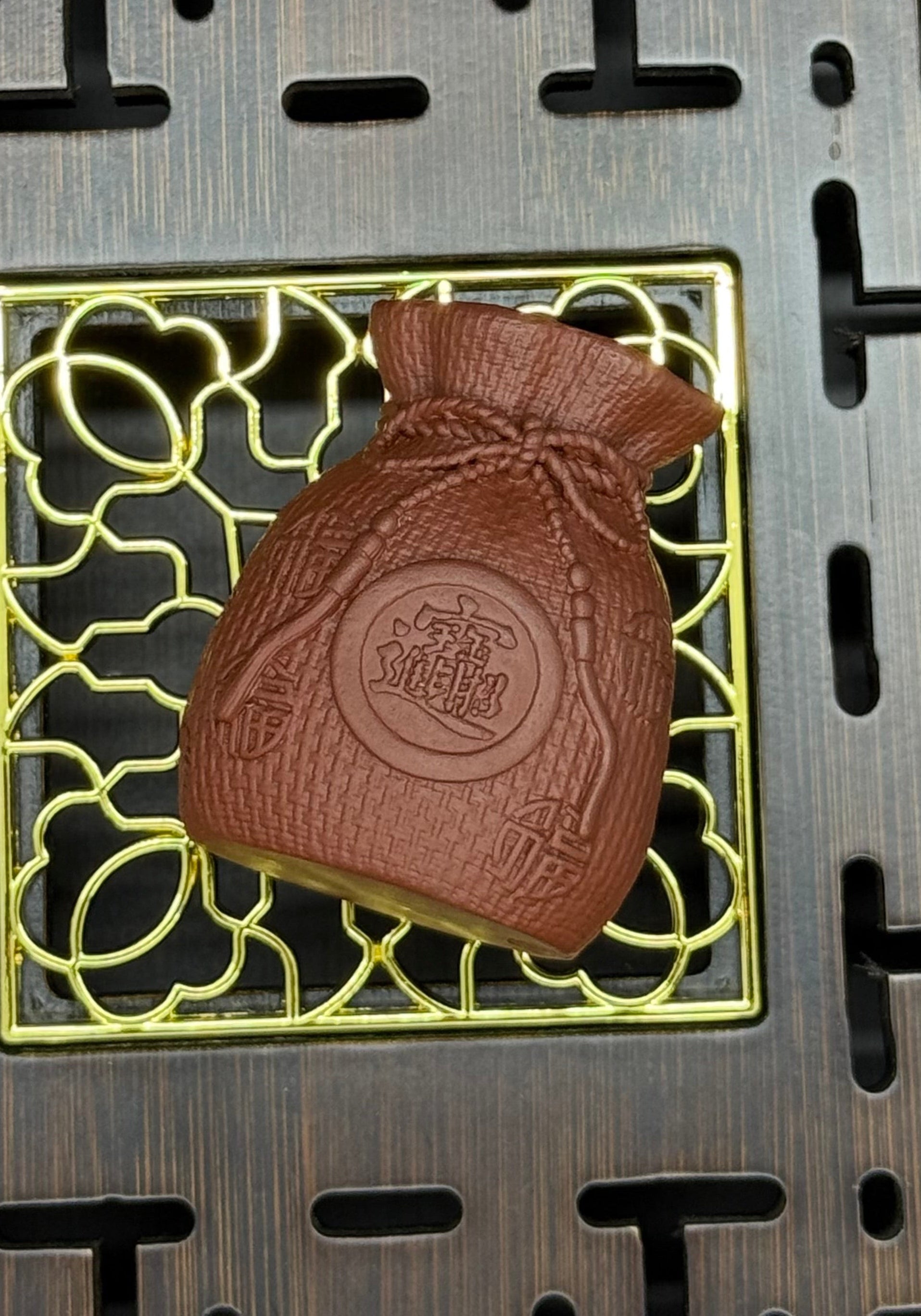 “Orange clay pouch tea figurine with coin motif”