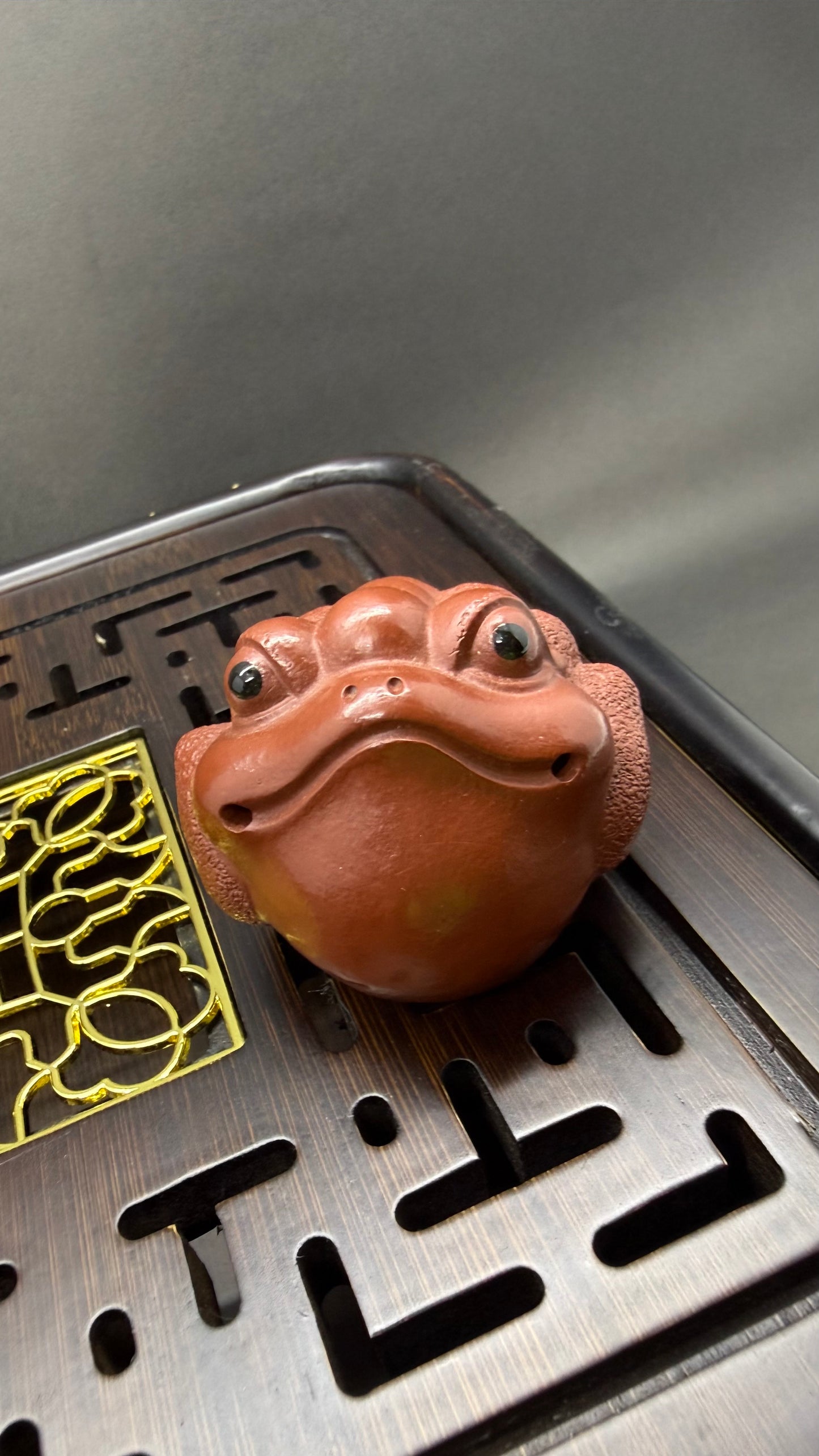 “Orange clay frog-head tea figurine”