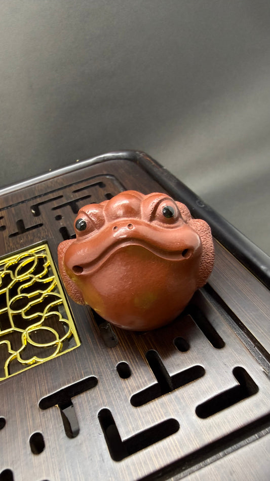 “Orange clay frog-head tea figurine”