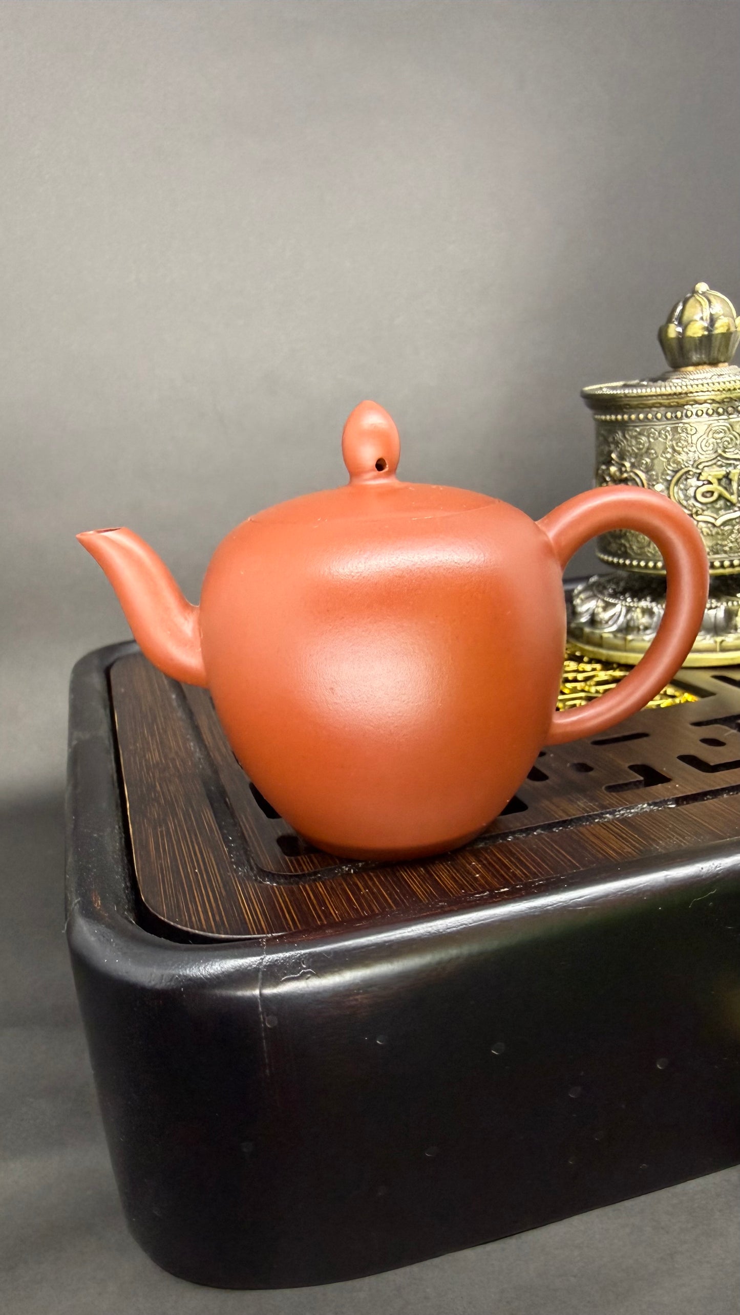 “Slightly oval orange Yixing clay teapot”
