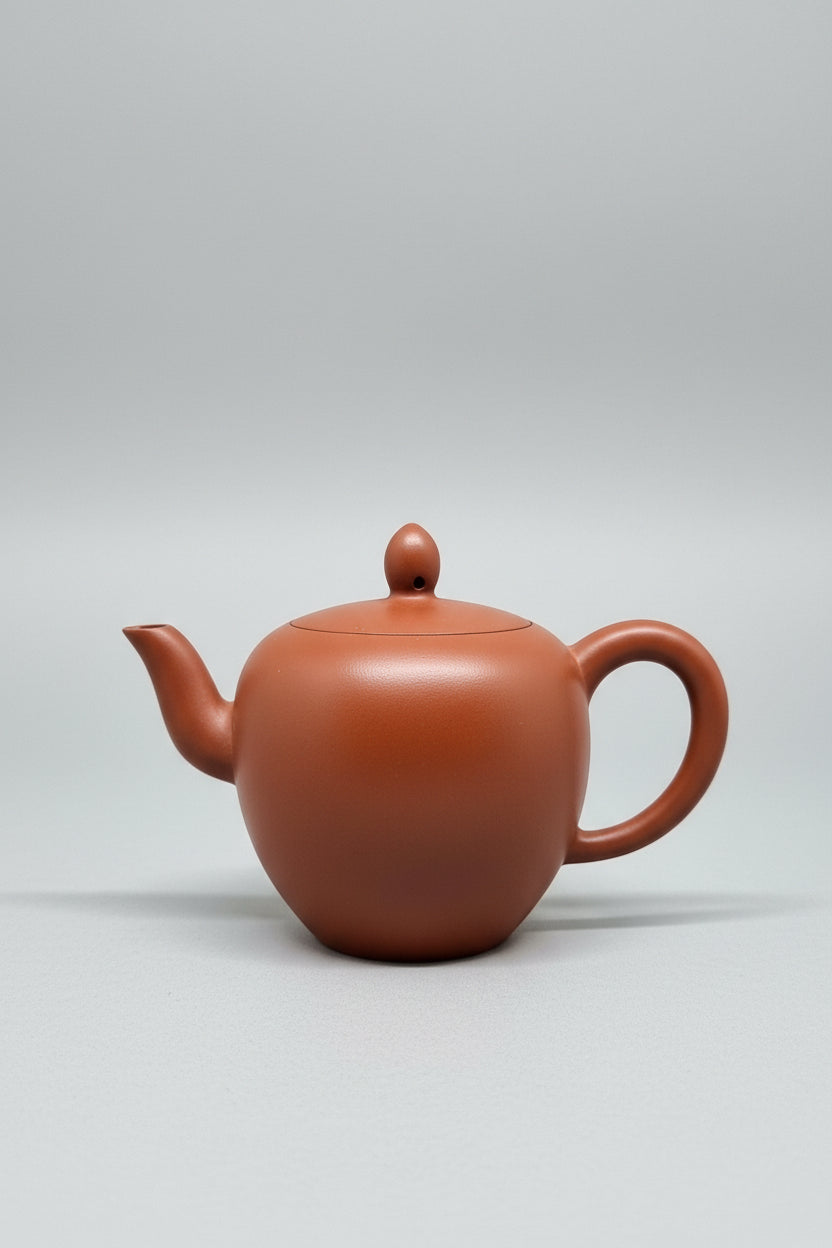 “Slightly oval orange Yixing clay teapot”