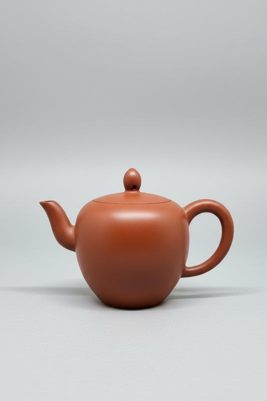 “Slightly oval orange Yixing clay teapot”
