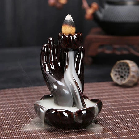 Black ceramic backflow incense burner with hand holding lotus flower design